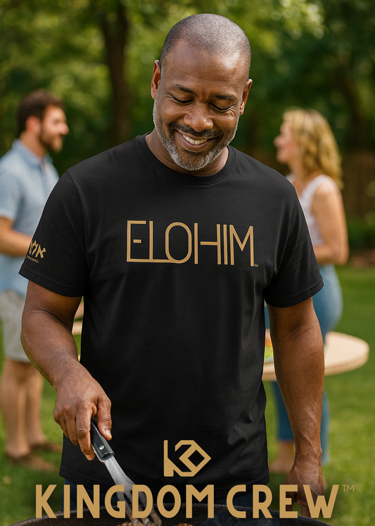 Man wearing a black 'ELOHIM' t-shirt with 'Kingdom Crew' branding, grilling outdoors.