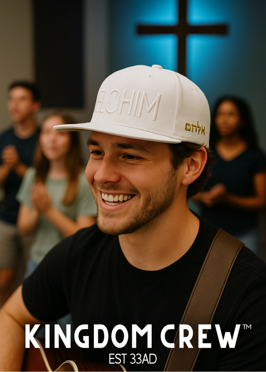 Man wearing a white cap with 'Yeshiim' embroidered on it, standing in front of a blurred group of people with a cross in the background.