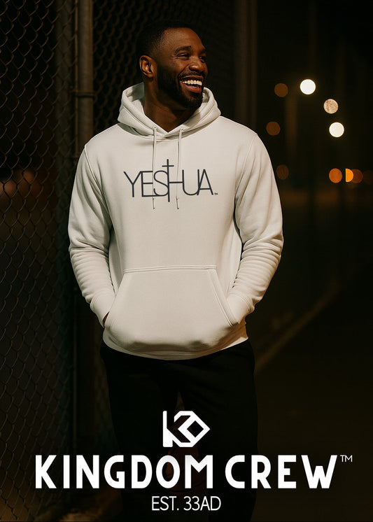 Man wearing a white hoodie with 'YESHUA' text, standing against a dark background with blurred lights.