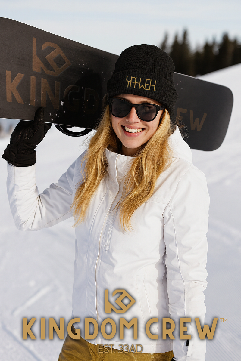 Person holding a snowboard with Kingdom Crew branding in a snowy setting