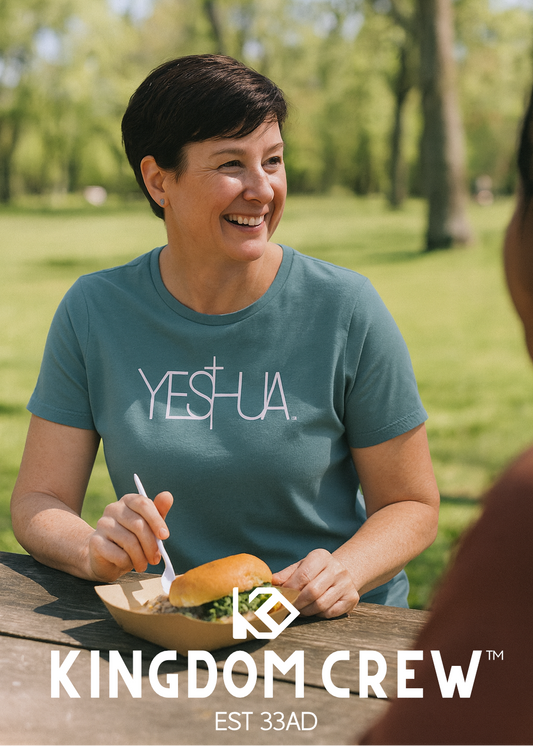 Woman in a teal 'YESHUA' t-shirt sitting outdoors with 'Kingdom Crew' branding.