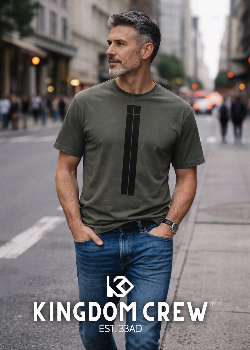 Man wearing a green t-shirt with a black logo on a city street, featuring the 'Kingdom Crew' brand.