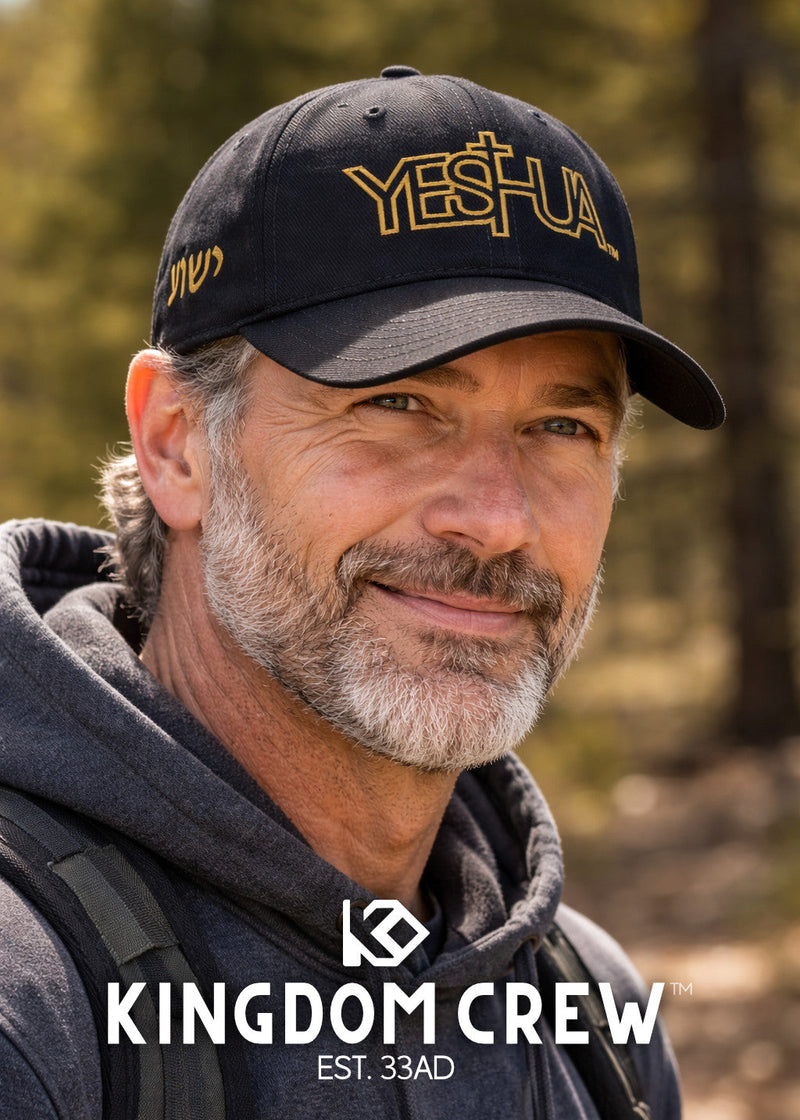 Man wearing a cap with 'YESHUA' and a hoodie, standing in a forest setting, with 'Kingdom Crew' branding.