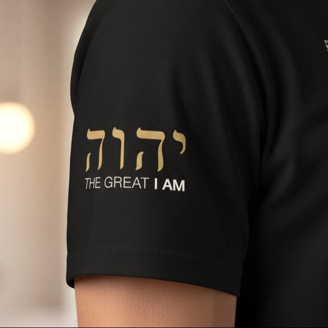 Black t-shirt with gold and white text on a blurred indoor background